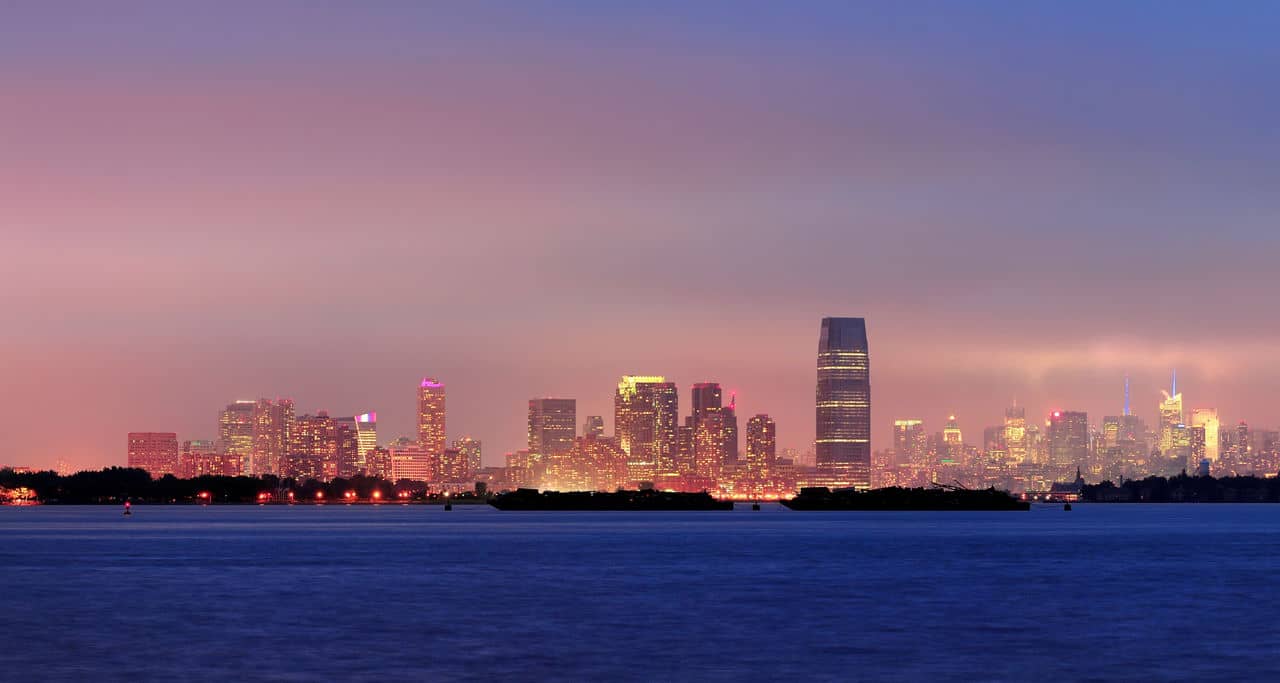 New Jersey skyline at night with skyscrapers over Hudson River.