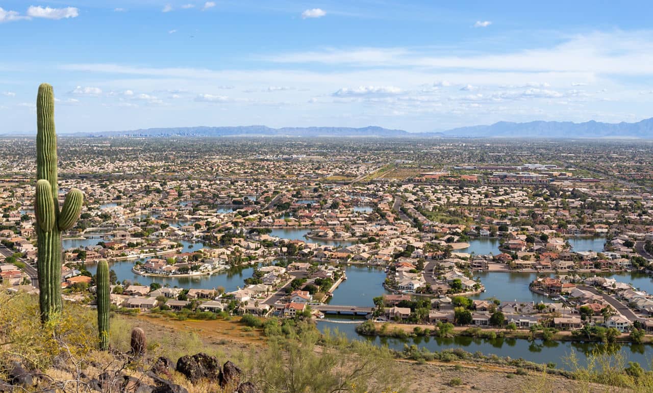 Aerial view of Glendale and Surprise Arizona residential neighborhoods with lakes and saguaro cactus in foreground - Phoenix West Valley panorama