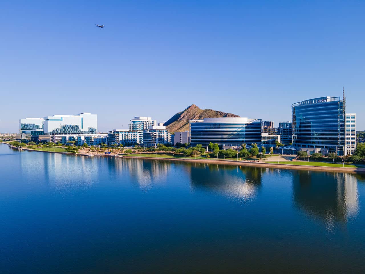  Tempe Town Lake waterfront with modern office buildings and Hayden Butte reflected in calm water - Tempe Arizona aerial view