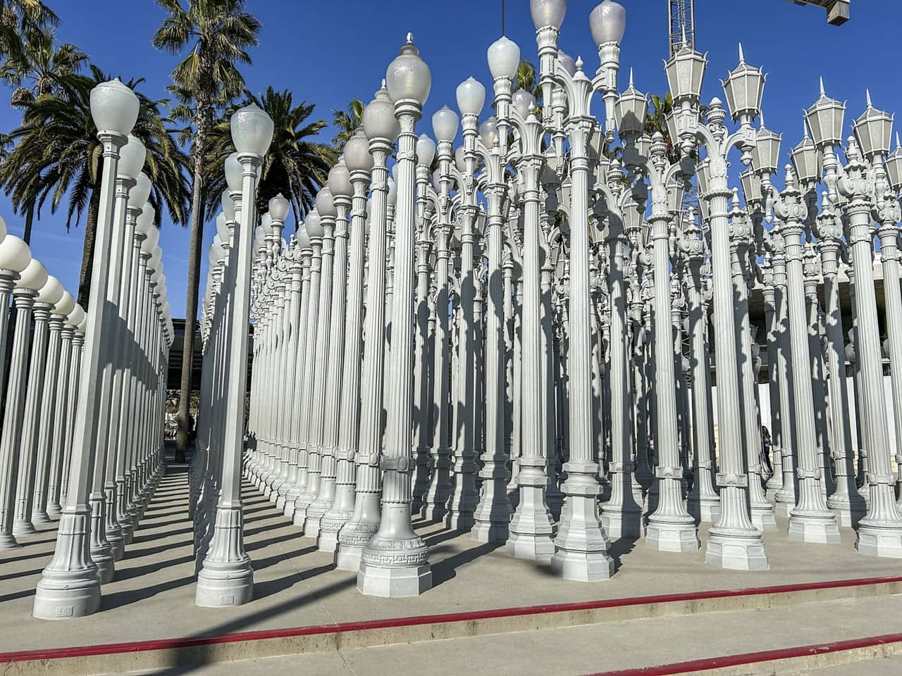 A close-up view of the &quot;Urban Light&quot; installation at LACMA in Beverly Grove/Mid-Wilshire, California, with rows of white lampposts under a clear blue sky.