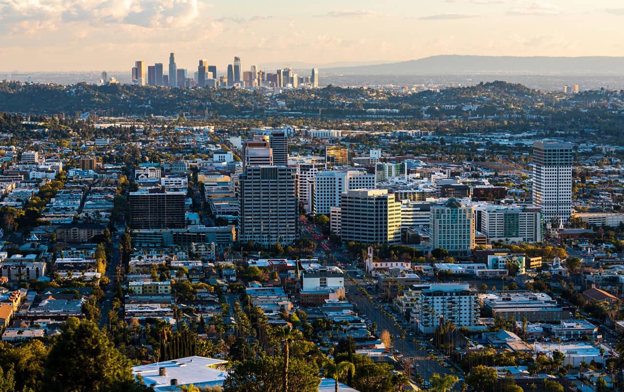A cityscape of Glendale, California, with tall buildings, busy streets, and a distant skyline under a clear sky.