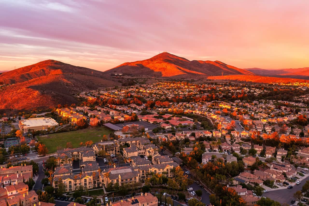 Aerial view of Chula Vista, California, during sunset with glowing hills, a residential neighborhood, and warm orange lighting.