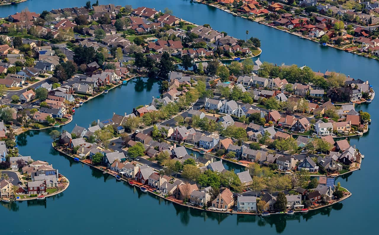 Aerial view of the San Mateo, California neighborhood with houses surrounded by blue waterways and lush greenery.