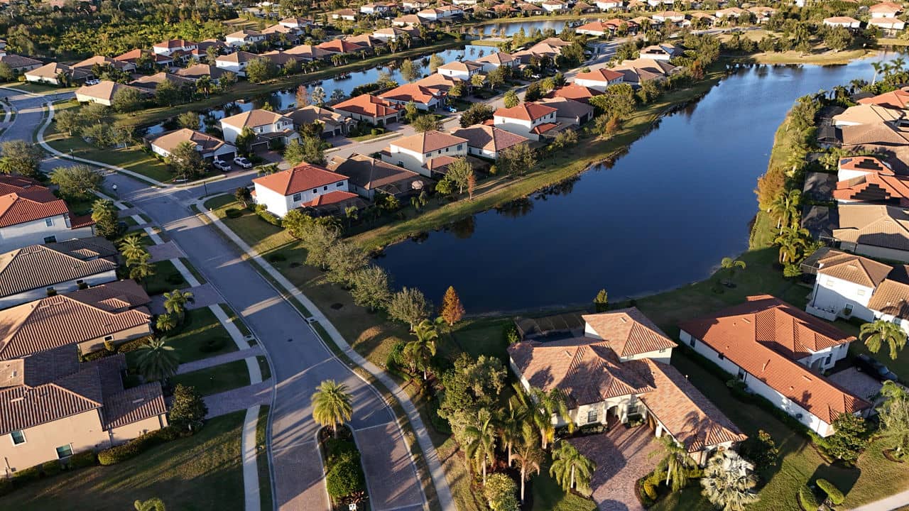 Aerial view of a suburban neighborhood in Lakewood Ranch, Florida, featuring waterfront homes, lush greenery, and winding streets.