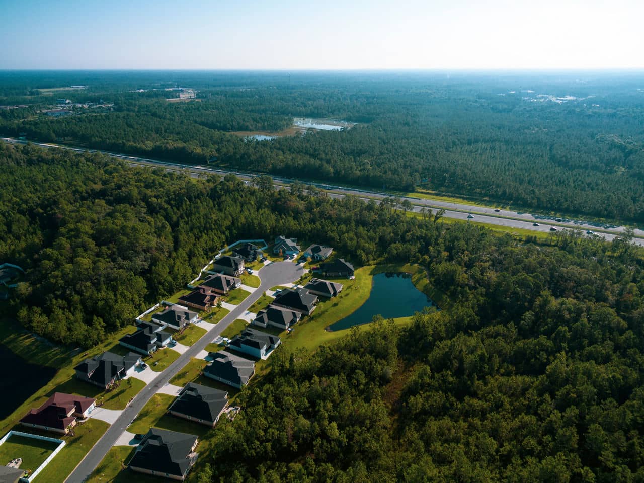 Aerial view of a suburban development in Town &apos;n&apos; Country, Florida with houses arranged along a cul-de-sac, surrounded by trees with a highway cutting through the landscape.