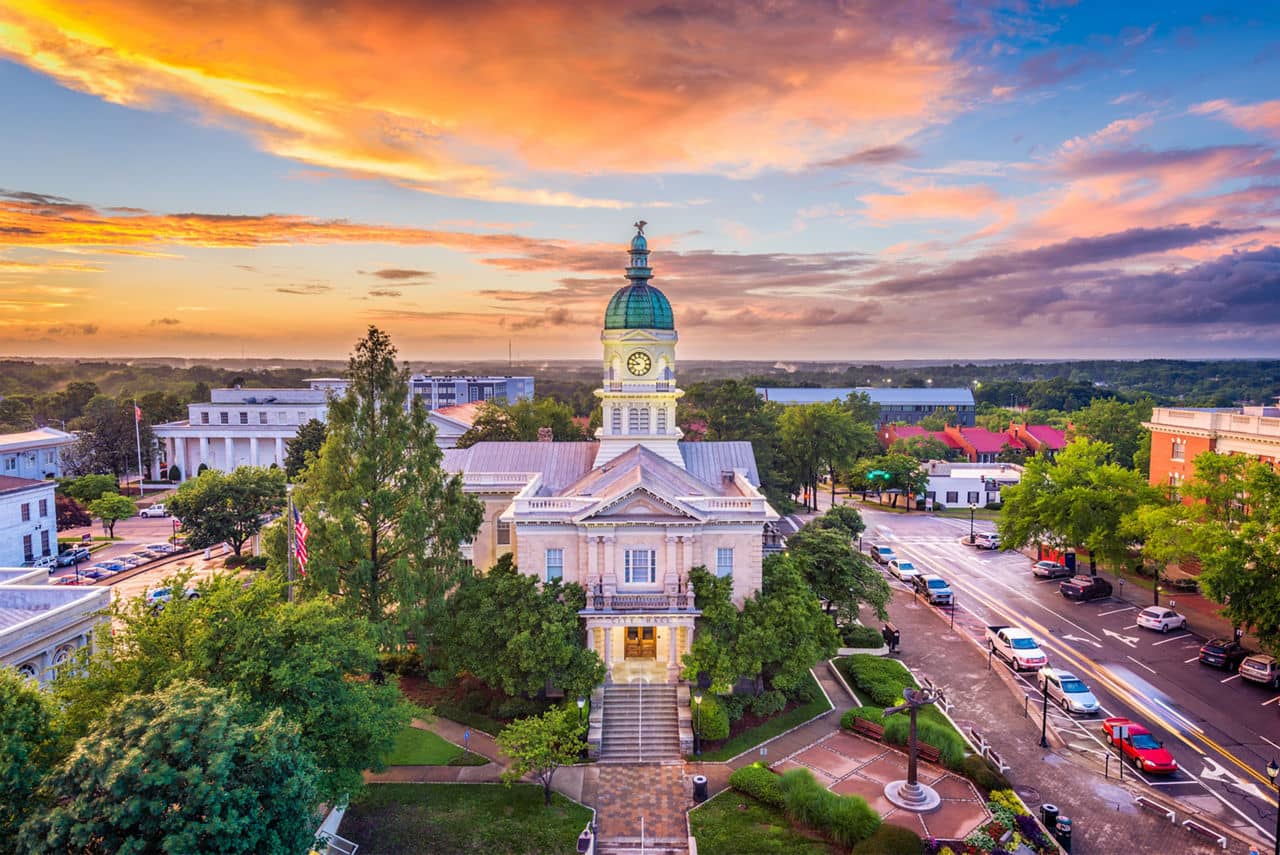 Historic courthouse with copper dome in downtown Athens, GA at sunset with colorful sky and surrounding buildings.