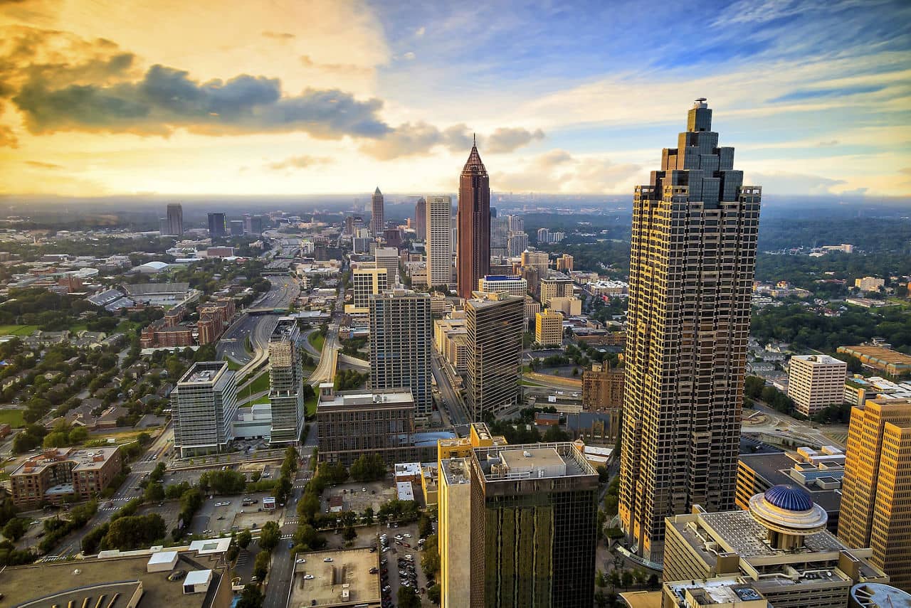 Aerial view of Perimeter Center, GA with skyscrapers catching sunset light and Atlanta skyline visible in background.