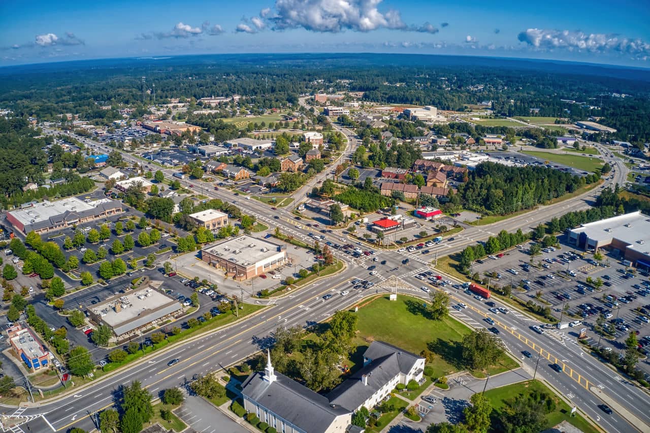 Aerial view of Evans/Martinez, GA showing a major intersection with a white church, shopping centers, and tree-lined streets.