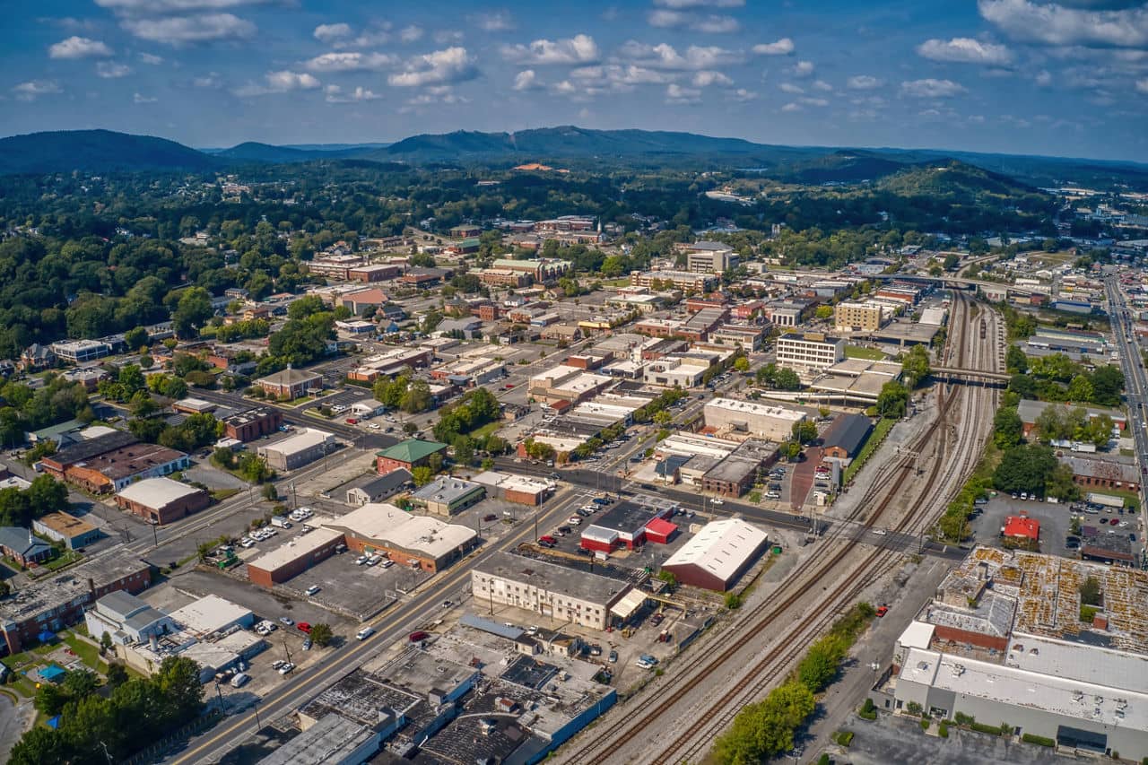 View of Dalton Metro, GA showing downtown area with railway tracks, small businesses, and blue mountains in the distance.