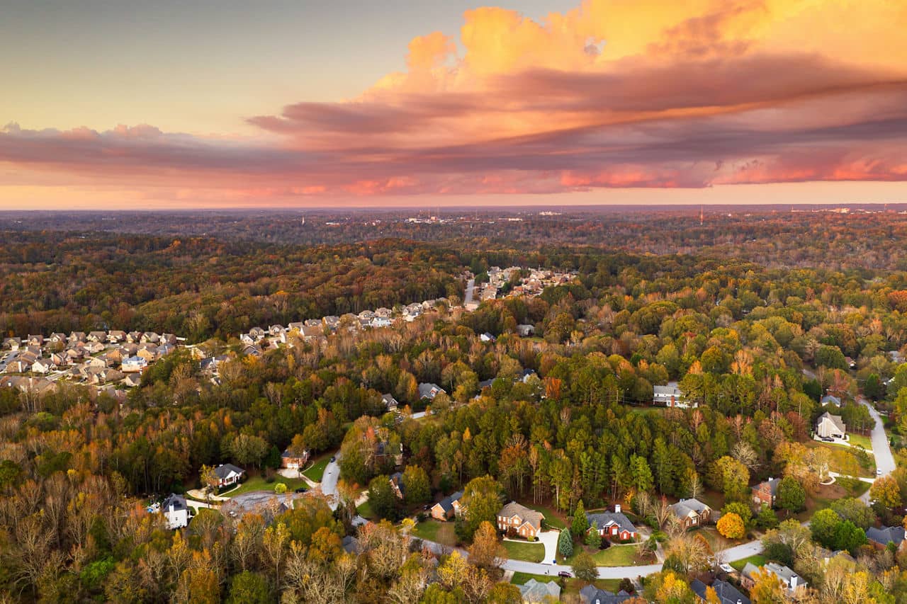Aerial view of Union City, GA showing suburban homes among autumn trees with colorful fall foliage under a sunset sky.