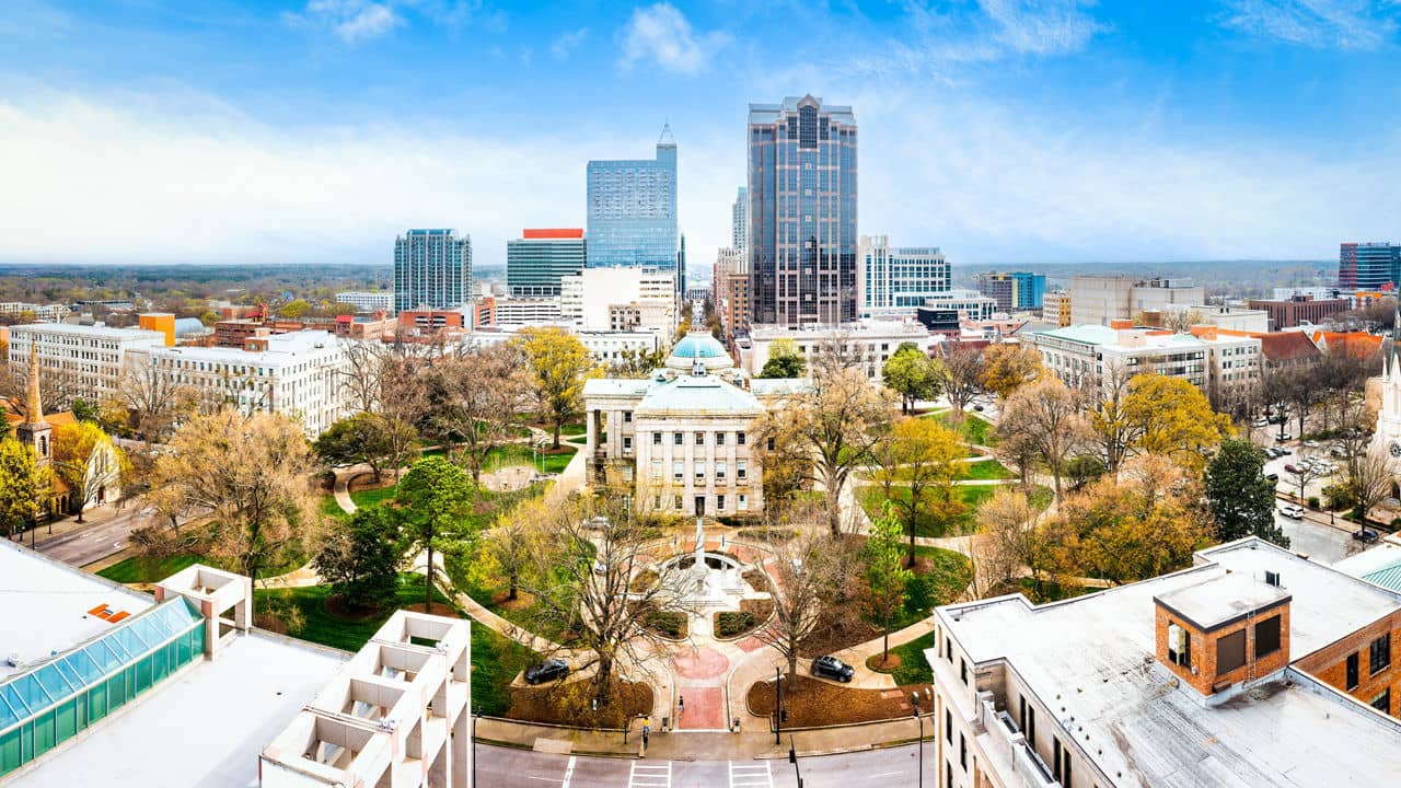 Aerial drone panorama of the historic North Carolina State Capitol building and modern downtown Raleigh city skyline at sunset, Raleigh, North Carolina.