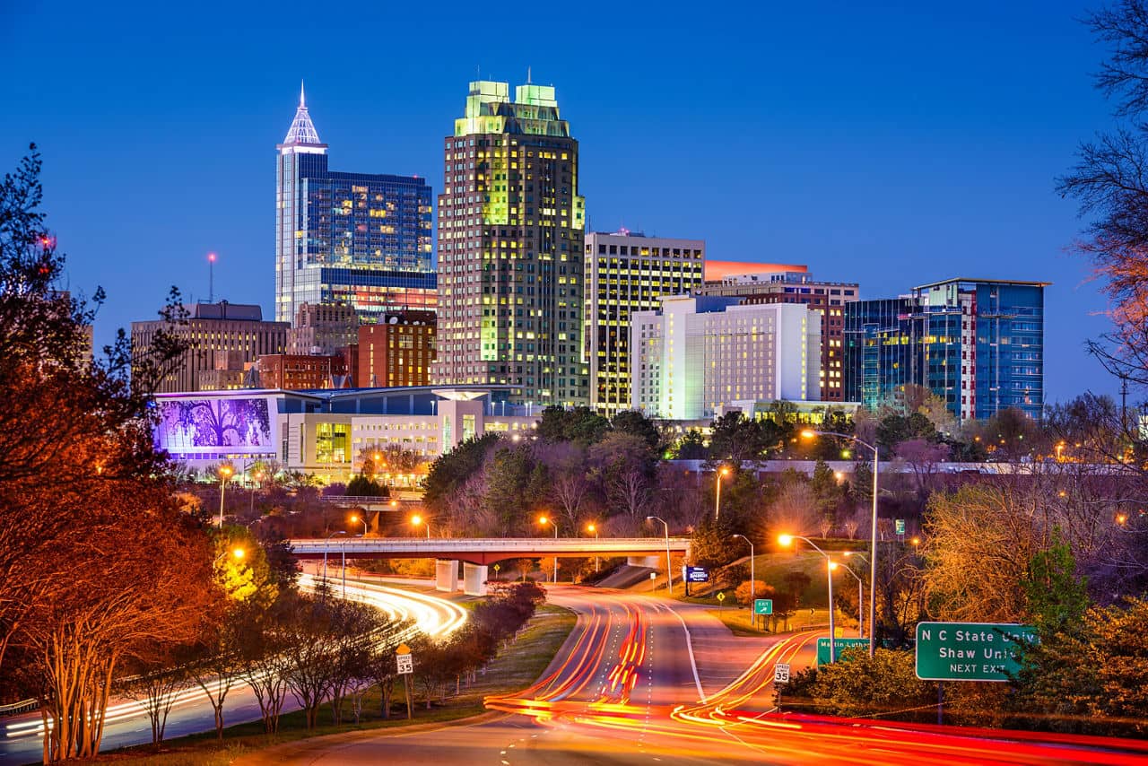 A beautiful panoramic photo of the downtown Raleigh cityscape and skyscrapers against a clear blue sky, this is Raleigh, North Carolina.