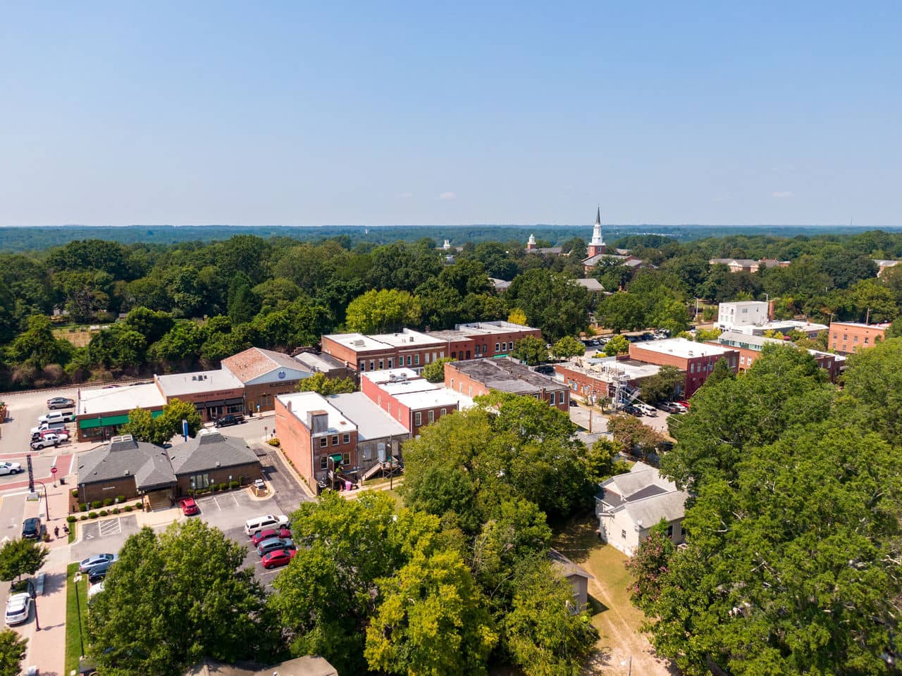 Sunny aerial drone photo highlighting the historic district, seminary, and new residential construction in downtown Wake Forest, North Carolina.
