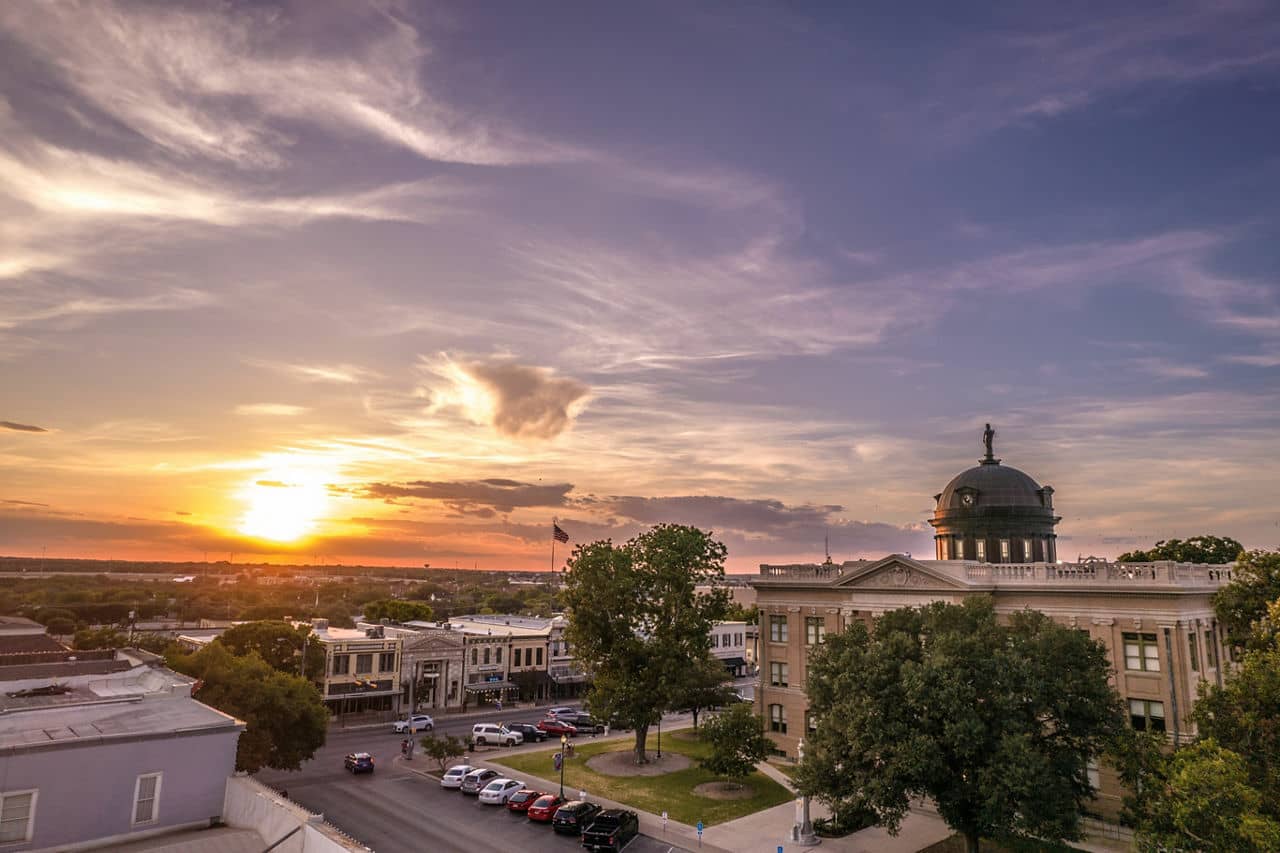 Architecture of Courthouse in Georgetown, Texas with street view, cars, greenery at sunset