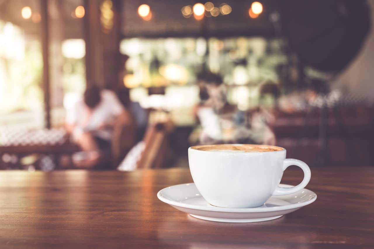 Cup of hot coffee on table in cafe with people. vintage and retro color effect - shallow depth of field