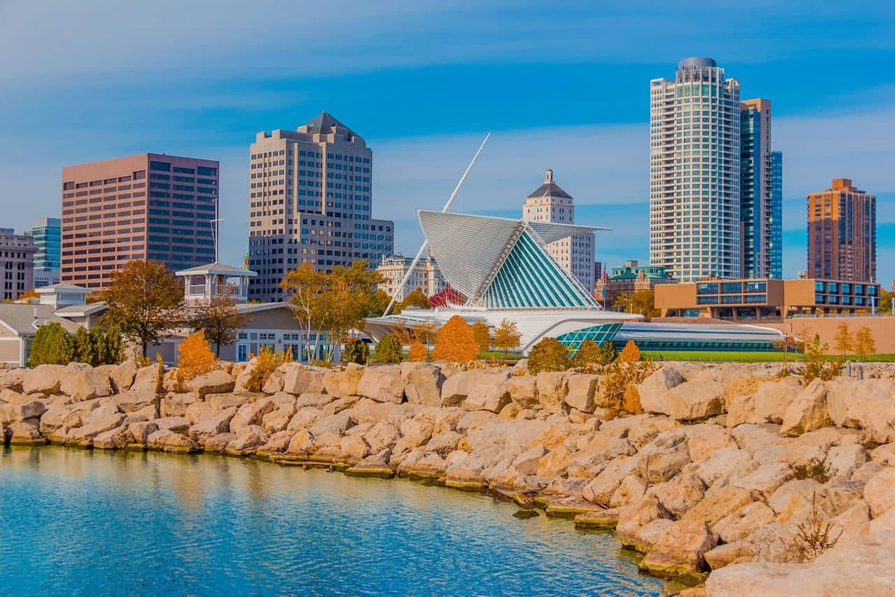 Skyscrapers fill the skyline of Milwaukee and Lake Michigan, WI. The rock breakwater forms a protective barrier against the water.